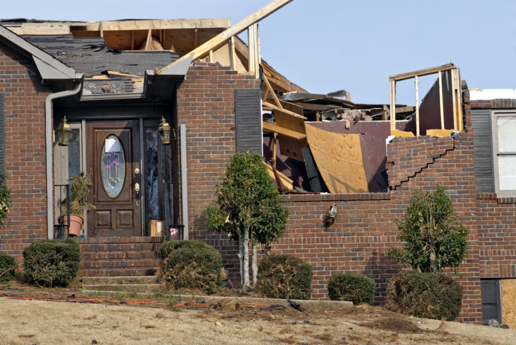 brown brick house destroyed by a tornado - bricks are split and have shifted as well as the entire roof being ripped off