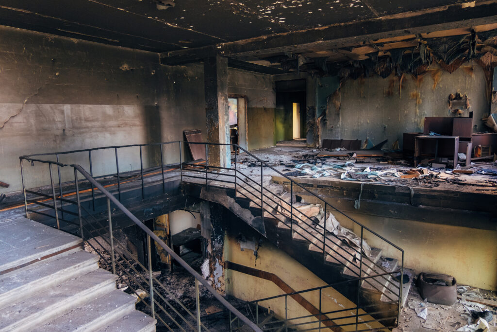 Burned interiors after fire in industrial building with walls and staircase covered in black soot