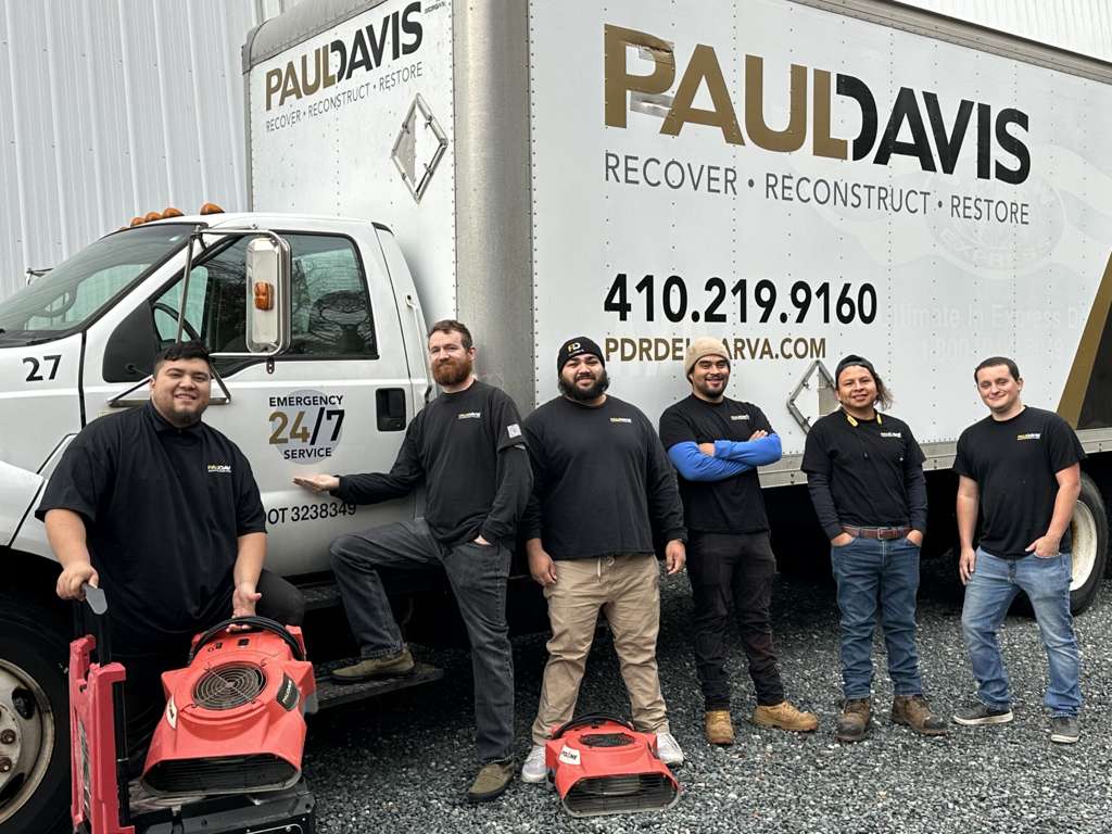 Paul Davis Restoration team standing with equipment in front of service truck, showcasing 24/7 emergency restoration services on the Delmarva Peninsula.